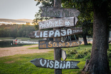 A wooden post with hand-painted signs pointing to various destinations, including 