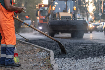 A male worker lays asphalt pavement to repair a road.