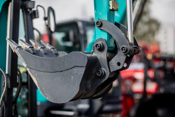 Brand new mini excavator black digging bucket with construction blade in the background at construction project