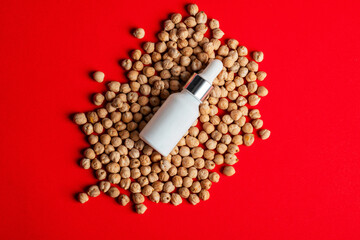 Plastic white tube for cream or lotion. Skin care or sunscreen cosmetic with chickpeas source of natural protein on red background.
