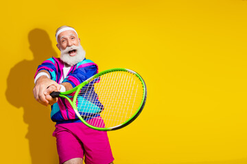Photo banner of sportive cheerful old man excited play tennis dressed stylish retro sportswear isolated on yellow color background