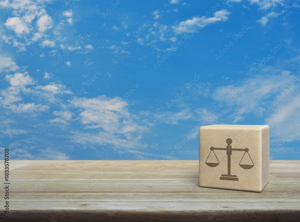 Wall mural law icon on wood block cube on wooden table over blue sky with white clouds, business legal service 