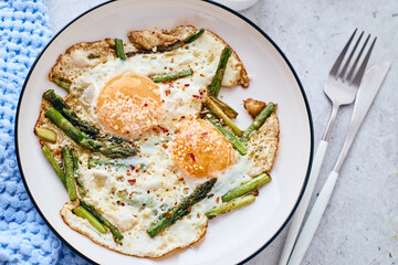 Fried eggs with asparagus and grated cheese. Breakfast concept.