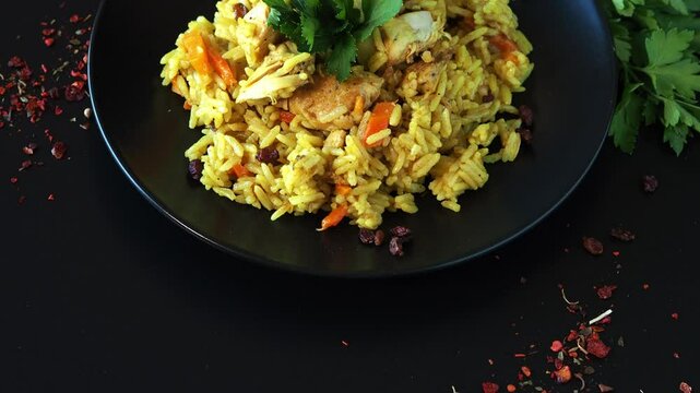 Pilaf on a black plate, on a black table. Uzbek cuisine food pilaf plov,Mutton,rice,carrots,vegetable oil,raisins,onion,turmeric,black pepper,cumin
