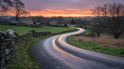 A meandering, curved country road across British countryside, illuminated by headlights.