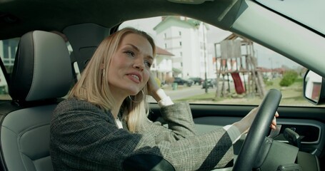 A business woman drives a car around the city on a sunny day. View from inside the car