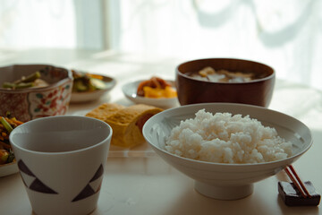 ヘルシーな日本の家庭料理の定食。ご飯・味噌汁・タラコのだし巻き・納豆・小鉢・漬物