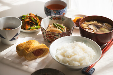 ヘルシーな日本の家庭料理の定食。ご飯・味噌汁・タラコのだし巻き・納豆・小鉢・漬物