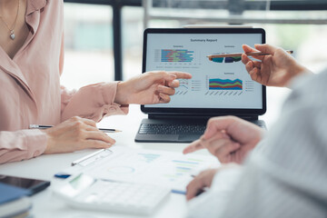 Business Analysis: Three professionals meticulously review data graphs on a laptop, collaborating...