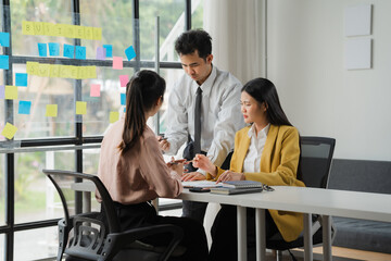 Collaborative Brainstorming: A diverse team of professionals collaborates on a project, with a man in a wheelchair, in a modern office setting. Post-it notes adorn the glass wall.