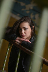 Beautiful young girl posing on a staircase of old abandoned building background.