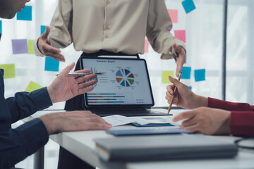 Business Strategy Meeting: A close-up shot of a diverse team engaged in a strategic discussion, reviewing a pie chart on a digital tablet.