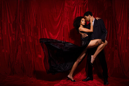 Photo of attractive tender gentle couple dancing hot salsa on stage isolated over red fabric background