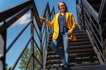 Middle-aged woman descending an outdoor staircase while looking at camera