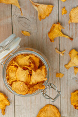 Dried chanterelles in a glass jar on a wooden table. Useful forest mushrooms. Cantharēllus cibārius. Selective focus