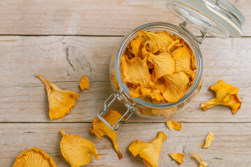 Dried chanterelles in a glass jar on a wooden table. Useful forest mushrooms. Cantharēllus cibārius. Selective focus
