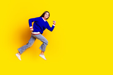 Full length photo of pretty teen girl jumping running fast wear trendy knitwear blue outfit isolated on yellow color background