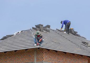 Roofer  installing concrete tiles on the roof house in residential construction site