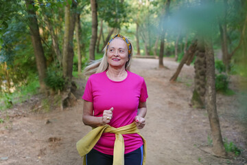 Senior woman jogging joyfully through a lush forest