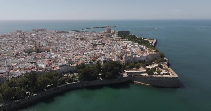 Aerial drone wide cityscape of C&aacute;diz in Spain, Andalusia, Europe, on bright sunny day, facing San Sebastian castle fortress and lighthouse and Baluarte de la Candelaria. Shot in 5K ProRes 422 HQ