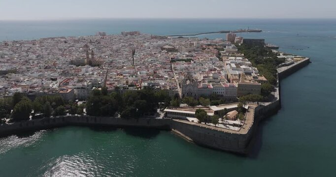 Aerial drone wide cityscape of C&aacute;diz in Spain, Andalusia, Europe, on bright sunny day, facing San Sebastian castle fortress and lighthouse and Baluarte de la Candelaria. Shot in 5K ProRes 422 HQ