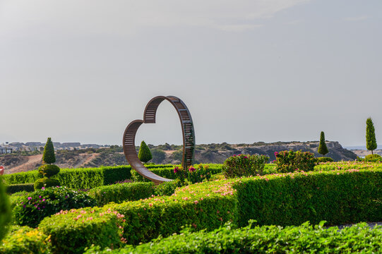 A heart-shaped sculpture surrounded by lush greenery in a serene garden at sunset, inviting moments of love and reflection