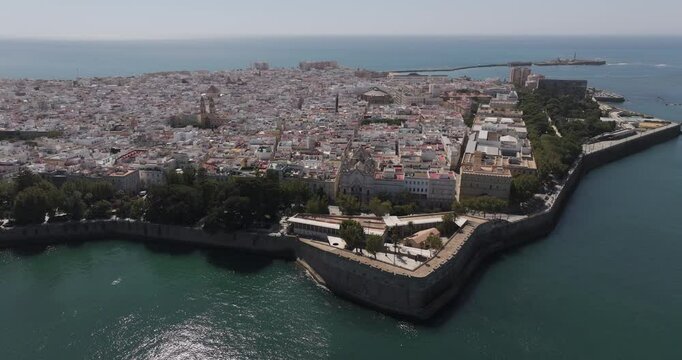 Aerial drone wide cityscape of C&aacute;diz in Spain, Andalusia, Europe, on bright sunny day, facing San Sebastian castle fortress and lighthouse and Baluarte de la Candelaria. Shot in 5K ProRes 422 HQ