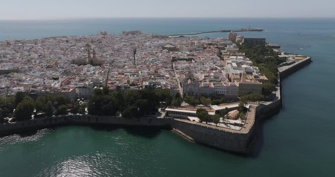 Aerial drone wide cityscape of C&aacute;diz in Spain, Andalusia, Europe, on bright sunny day, facing San Sebastian castle fortress and lighthouse and Baluarte de la Candelaria. Shot in 5K ProRes 422 HQ