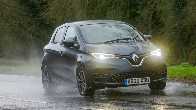 2020 grey Renault Zoe electric car driving on a wet road, in the rain with headlights on