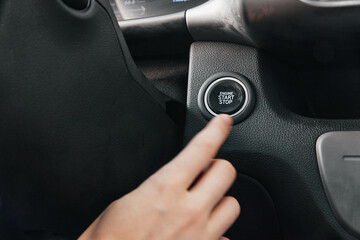 Car steering wheel closeup person pressing button to start or stop vehicle, showcasing modern automotive technology, handson interaction with car controls