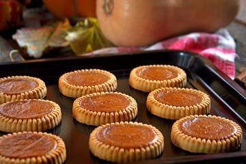 Mini pumpkin pies on a baking tray. Selective focus.
