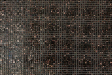 Close-up view of a textured mosaic wall showcasing intricate patterns in various shades of dark colors