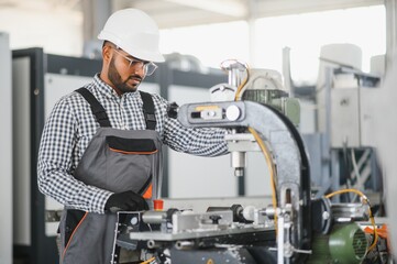 Portrait of cheerful young worker wearing hardhat at modern factory