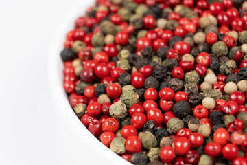 A mixture of different peppercorns on a white background