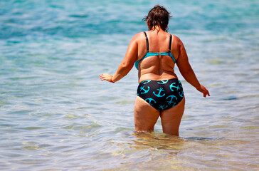 A woman in a bikini is standing in the ocean