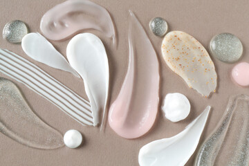 Smears of different cosmetic products on grey background, flat lay