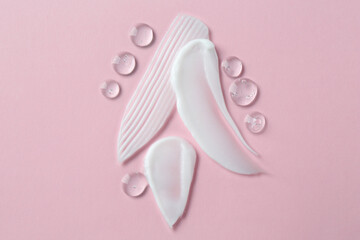Smears of different cosmetic products on pink background, top view