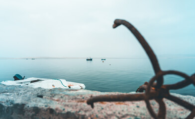 Fototapeta premium A rusty anchor is on the side of a wall next to a body of water