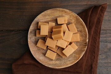 Tasty sweet caramel candies on wooden table, top view