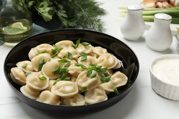 Delicious pelmeni with green onion served on light table, closeup