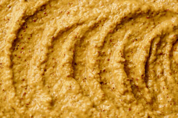 Mustard sauce with grains close-up. Hot spices as a background. Texture of Dijon mustard.
