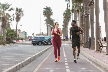 A couple jogging together on a coastal pathway lined with palm trees during a sunny day in a vibrant beach community