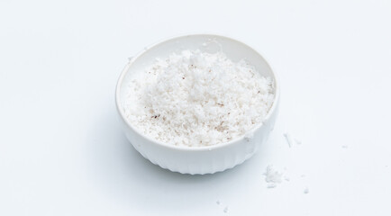 Coconut flakes in ceramic bowl on white background