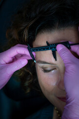 Obraz premium Aesthetic eyebrow treatment in a beauty salon with a Colombian stylist and a young Spanish woman