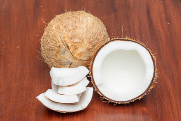 Whole mature coconut, half cut and pieces on wooden background