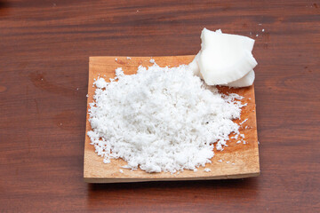 Grated coconut set on wooden board with pieces of coconut fruit
