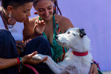Lesbian couple Interacting with Dog as it Offers Its Paw in Exchange for a Treat