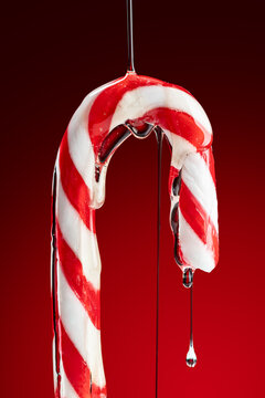 Sauce drizzling on a candy cane against a red background