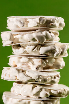 Stacked slices of white nougat turron de Alicante on green background