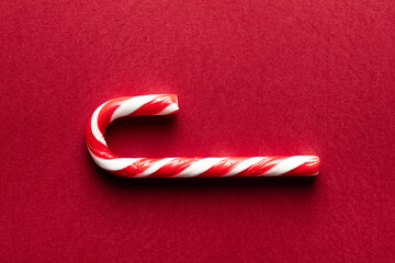 Top view of a single candy cane on a red background